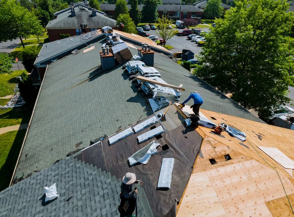 Aerial view of roofers tearing off and re-decking a residential roof