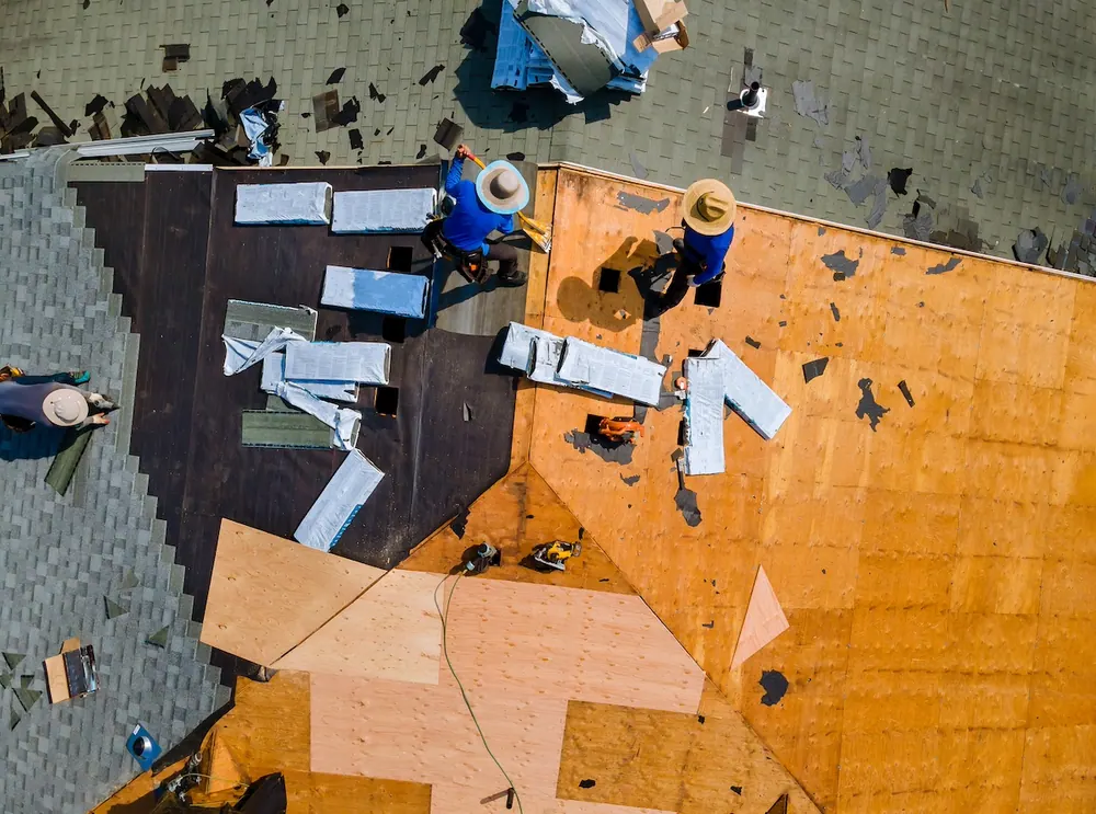 Aerial view of a roofing crew installing underlayment on a residential roof